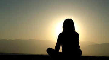 A woman doing zen meditation under sunset